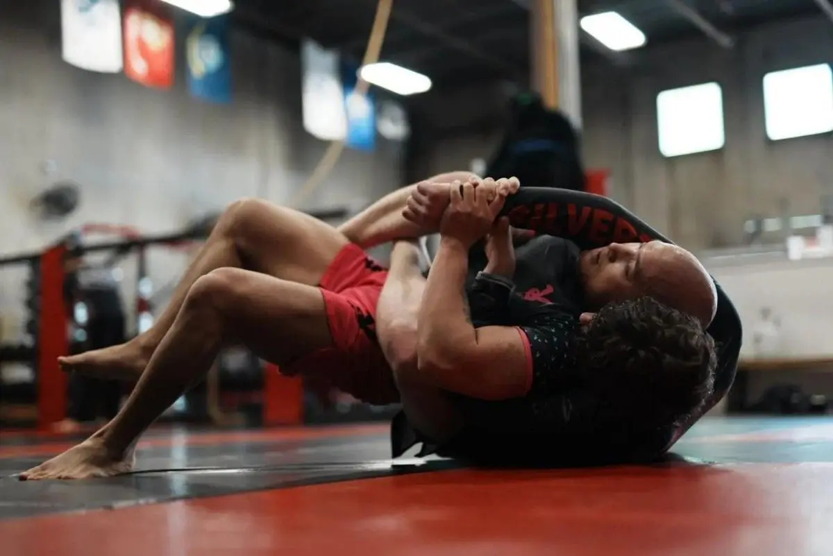 Adult students practice ground control and submission drills during a Brazilian Jiu-Jitsu self-defense class.