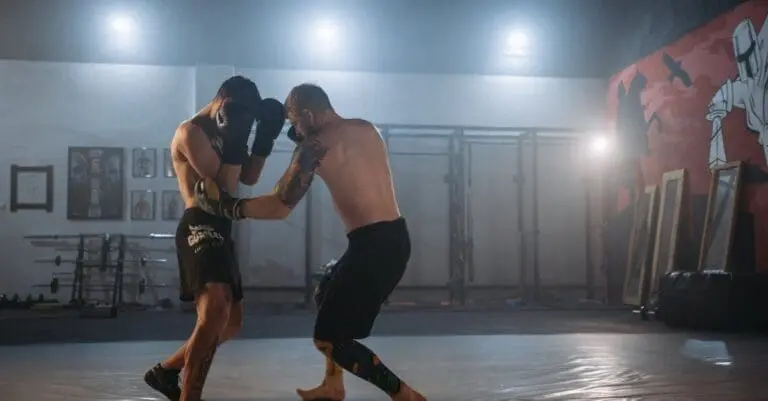 Two fighters practicing striking in a gym, demonstrating a defensive guard and balanced weight distribution essential for proper Muay Thai stance and footwork.